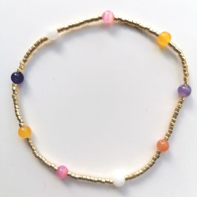Elastikarmbånd, Et spinkelt armbånd med lyse perler og små farveglimt i rosa, lilla og gyldne toner – diskret alene og fint i lag.