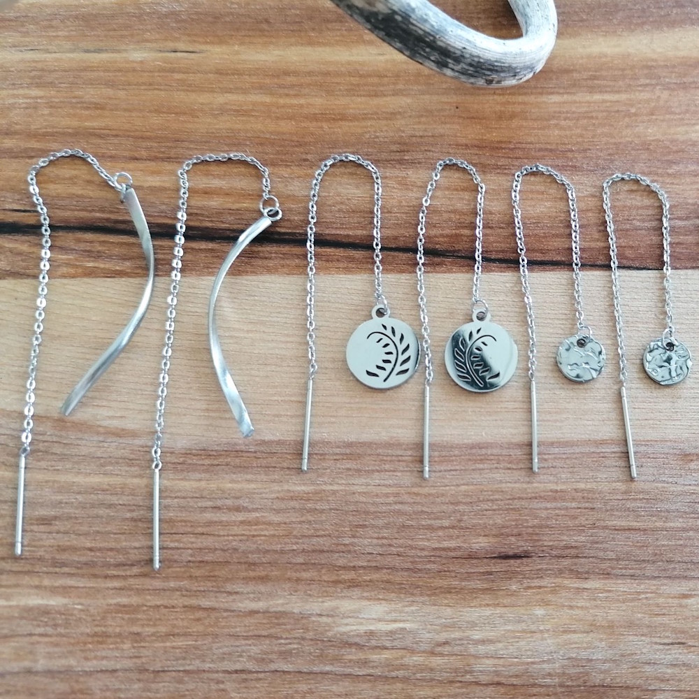 Øretråd med vedhæng, En lille samling lange øretråde med fine symboler og vedhæng, fra runde ornamenter til lette stjerner med grafisk silhuet.
